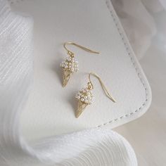 Get ready to satisfy your sweet tooth with these Ice Cream Cone Earrings! Made with sterling silver hoops, these delectable dangles are plated with 14K yellow gold for a touch of elegance. Measuring 3.5cm x 1cm, they feature charming pearl accents for a trendy and unique look. Perfect for any fashionable foodie, these earrings are a playful addition to your summer accessory collection. Trendy 14k Gold-filled Drop Earrings, Trendy 14k Gold Filled Drop Earrings, Trendy Gold Plated Earrings For Gifts, Gold Single Pearl Earring In Sterling Silver, Gold Color Sterling Silver Single Pearl Earring, Gold Sterling Silver Earrings With Pearl Drop, Gift Pearl Earrings With Metal Plating, Metal Pearl Earrings With Plating For Gifts, Metal Plated Pearl Earrings For Gifts