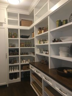 an organized pantry with white shelves and wooden counter tops