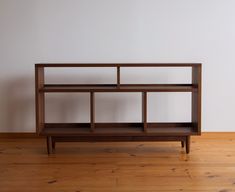 a wooden shelf sitting on top of a hard wood floor next to a white wall