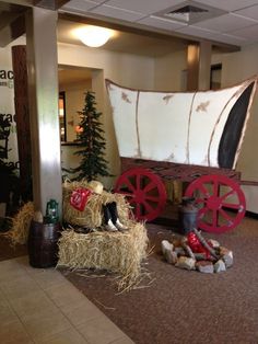 a horse drawn wagon sitting in the middle of a room filled with hay and other items