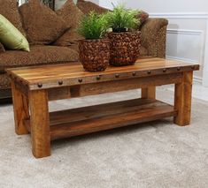 two potted plants sit on top of a wooden table in front of a couch