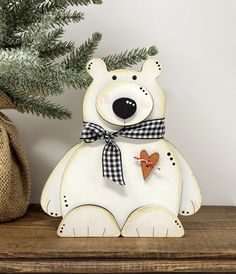 a white bear sitting on top of a wooden shelf next to a potted plant