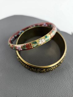 Vintage Bangle Set  The gorgeous Red Pink Blue Green Enamel Brass Floral Bracelet has the Floral Pattern on the inside as well. Vintage condition: These bracelets are vintage and show some age and wear. The brass has some tarnishing. The black paint on the black and brass bracelet has worn off and has scratches in several areas. Please take a close look at all of the images. Bracelet Dimensions: Red Pink Blue Green Enamel Brass Floral Bracelet: diameter on inside of bracelet: 2 1/2" (6.4 cm) width of bracelet: 3/8" (1 cm) Black and Brass Floral Bracelet: diameter on inside of bracelet: 2 9/16" (6.5 cm) width of bracelet: 1" (2.5 cm) Feel free to contact me with any questions. shop additional items in my vintage shop: http://MeganLeoneVintage.etsy.com Rose Bleu, Floral Bracelet, Vintage Bangles, Brass Bracelet, Black And Brass, Green Enamel, Bangle Set, Black Paint, Vintage Shops