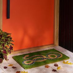 a green door mat sitting next to a potted plant