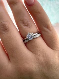 a woman's hand with a diamond ring on top of her finger and an engagement band