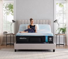 a woman sitting on top of a mattress in a room