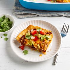 a slice of mexican pizza on a plate with a fork and bowl of cilantro