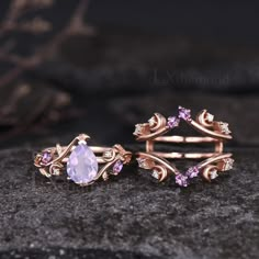 two gold rings with amethorate and pink sapphires are sitting on top of a rock