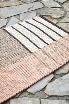 a close up of a rug on a stone floor with stones and rocks in the background