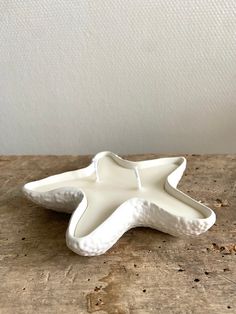 a white ceramic starfish dish sitting on top of a wooden table