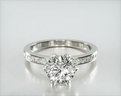 a diamond engagement ring with channel set diamonds on the band and an 18k white gold band