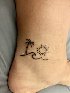 a small tattoo on the foot of a person with a sun and palm tree in the background