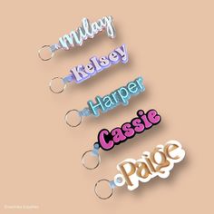 the name keychains are all different colors and styles, including pink, blue, purple