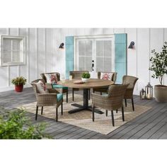 an outdoor dining table with chairs and potted plants