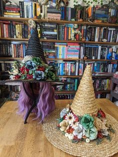 two witches hats sitting on top of a wooden table next to bookshelves filled with books