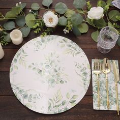 there is a place setting on the table with flowers and greenery next to it