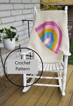 a white rocking chair with a crochet rainbow quilt on it's back