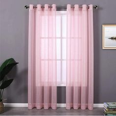 a pink curtain hanging on the side of a window next to a potted plant