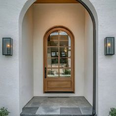 an arched doorway with two potted plants on either side and the entrance to a home