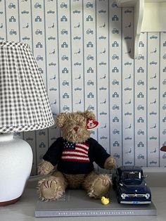 a teddy bear sitting on top of a table next to a lamp and toy car