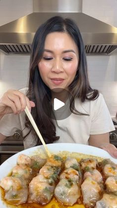 a woman holding a white plate filled with food and chopsticks in front of her face