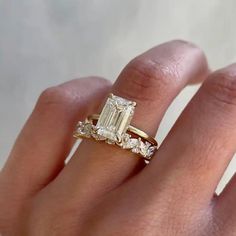 a woman's hand with a diamond ring on top of her finger and an engagement band