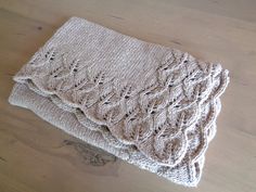 two knitted blankets sitting on top of a wooden table