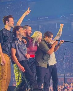 a group of people standing on top of a stage with microphones in their hands