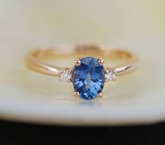 "This Engagement ring features a Cornflower blue sapphire in oval cut. The sapphire is natural untreated, eye clean and sparkling. It is set in a 3-stone setting flanked by 2 diamonds. This ring would make a perfect engagement ring, anniversary ring or promise ring. The setting is 14k Rose gold, diamonds SI/H. Details: Center stone: Sapphire approx. 1.15ct (5x7mm)  natural, unheated, SI clarity Accented stone: Diamonds: SI/H, TDW 0.1ct This ring is ready to ship. We offer FREE SHIPPING Worldwide Oval Engagement Ring 3 Stone, Engagement Ring 3 Stone, Engagement Ring Gemstone, Ring 3 Stone, Morganite Engagement Ring Set, Pink Morganite Engagement Ring, 3 Stone Ring, Cheap Engagement Rings, Oval Engagement Ring