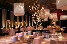 a room filled with lots of tables covered in white cloths and lit up chandeliers