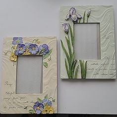 two frames with flowers painted on them sitting next to each other