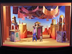 two people standing in front of a stage set for the musical show's production