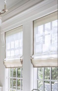 two windows with roman shades in a white room