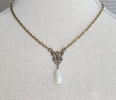 "This beautiful necklace features a beautiful brass filigree pendant with glass pearl teardrop. The necklace is reminiscent of pieces seen in classic portraits of the past. It hangs 16 1/2 \" long from a nickel free brass chain with lobster clasp and has a 2\" long extender chain with glass pearl detailing. Comes in a lovely gift box with ribbon. In the Eighteenth and Nineteenth centuries necklaces were very fashionable. Some were made of pearls, glass or gemstones and can be seen in many classic portraits. I think they're a very elegant accessory." Wedding Filigree Teardrop Necklace, Elegant Handmade Antique Gold Necklace, Bronze Necklace With Intricate Design For Formal Events, Antique Gold Necklace With Antique Finish For Wedding, Antique Gold Wedding Necklace With Antique Finish, Vintage Filigree Teardrop Jewelry, Victorian Pearl Necklace For Formal Occasions, Vintage Teardrop Filigree Jewelry, Elegant Pendant Necklaces With Historical Design