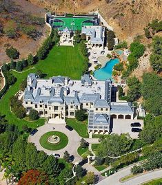 an aerial view of a large mansion in the middle of trees and hills with a pool