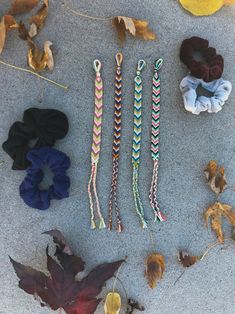 four different colored hair ties laid out on the ground next to leaves and other items