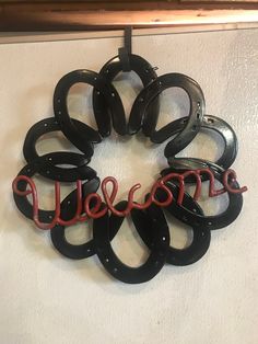 a metal wreath with the word welcome hanging from it's side on a wall