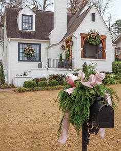 a mailbox decorated with greenery and bows in front of a white house on a fall day