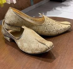 a pair of gold shoes sitting on top of a wooden table next to a mirror