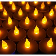 many lit candles are arranged in rows