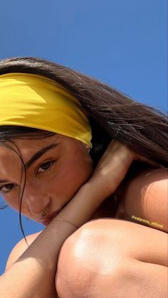 a woman wearing a yellow headband and looking off into the distance with her hands on her hips