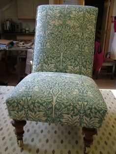 a green and white patterned chair sitting on top of a floor next to a table