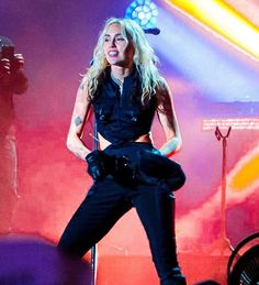 a woman standing on top of a stage in front of microphones and lighting equipment