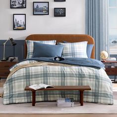 a bed with blue and white plaid comforter in front of pictures on the wall