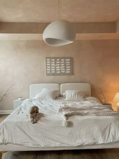 a white bed sitting in a bedroom on top of a hard wood floor next to two lamps