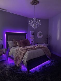 a bedroom with purple lighting and a leopard print comforter on the bed in front of a chandelier