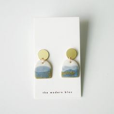 a pair of earrings with blue and white designs on them sitting on top of a card