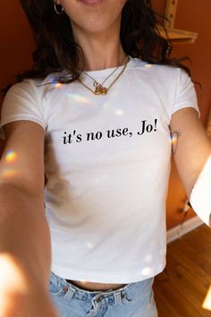 It's No Use, Jo! 90s Baby Tee, Aesthetic Tee, Women's Fitted Tee, Unisex Shirt, Trendy Top, Little Women Quote Shirt, Y2K 90s Baby Tee DETAILS - 100% cotton (fiber content may vary for different colors) - tear-away label  SIZING Please find the size chart in the listing photo before purchasing. PLEASE NOTE: Our Baby tee is sized for a youth, reminiscent of the '90s-era shrunken-down T-shirt. This style, popularized by the skater/raver culture of the time, is not to be confused with the modern crop top. The baby tee was the equivalent of a kids' size medium or large and reflected the child-inspired fashion trend of that era. I suggest taking a tee or singlet you already enjoy wearing and measuring it to compare with the dimensions provided size chart in the listing photo, in order to find t Its No Use Jo Tee, Quote Tshirts Women, 90s Style Crew Neck Top With Text Print, Unisex Slogan Crew Neck Top, 90s Slogan Crew Neck Top, Fun Slogan Crew Neck Top, Fitted Tops With Funny Text, 90s Style Relaxed Fit Tops With Text Print, Unisex Fun Tops For Streetwear