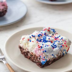 a piece of cake with white frosting and sprinkles on a plate