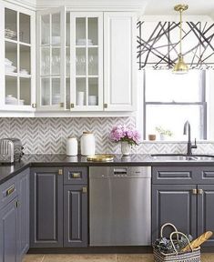 a kitchen with gray cabinets and stainless steel dishwasher in the center, along with a basket full of utensils on the counter